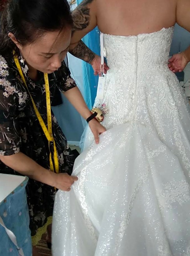 Ava hand-finishing a bridal gown fitting in the studio